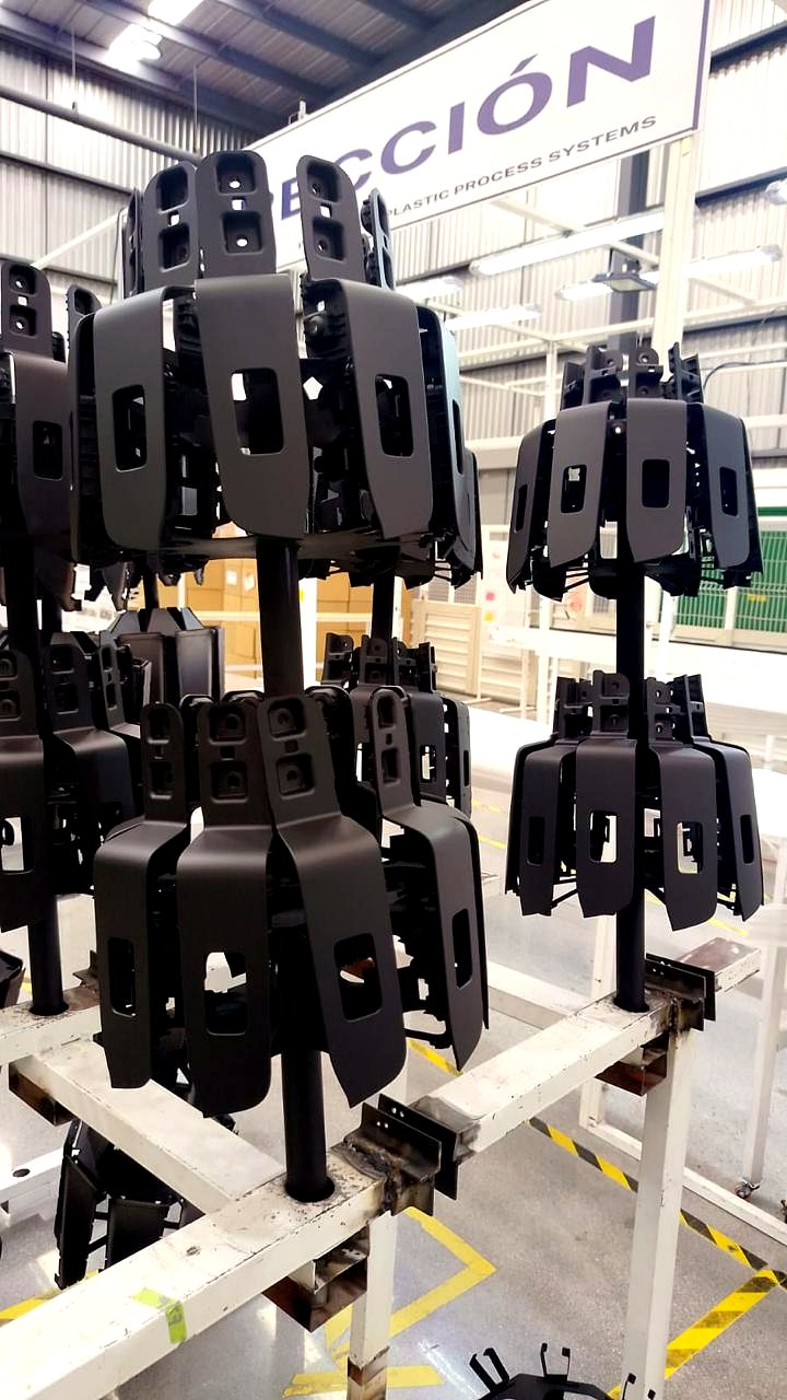 Piezas plásticas colocadas en racks de pintura